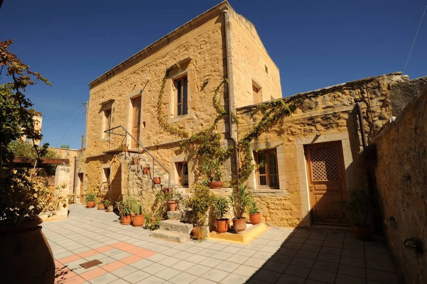 Villa Alexandrou stone facade draped in vines at golden hour